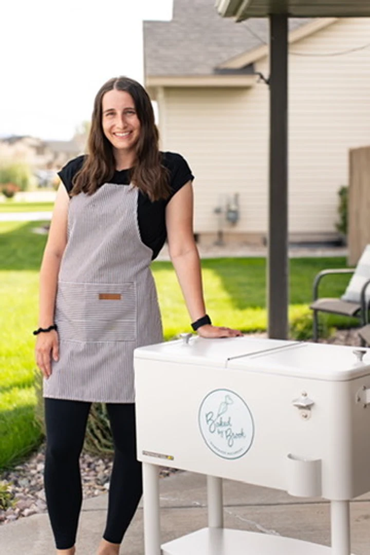 Brook, the baker behind Baked by Brook, smiling next to her Baked by Brook cart outdoors