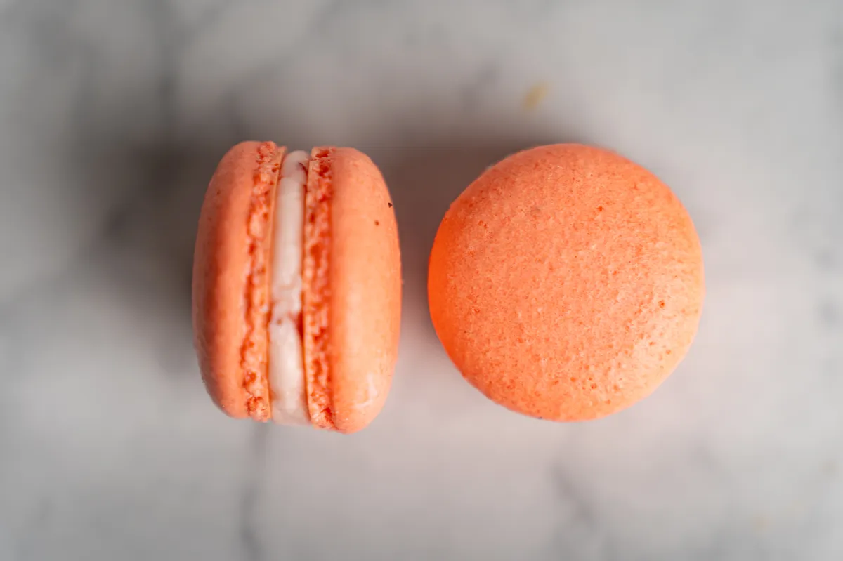 Coral strawberry macarons with cream filling on white marble