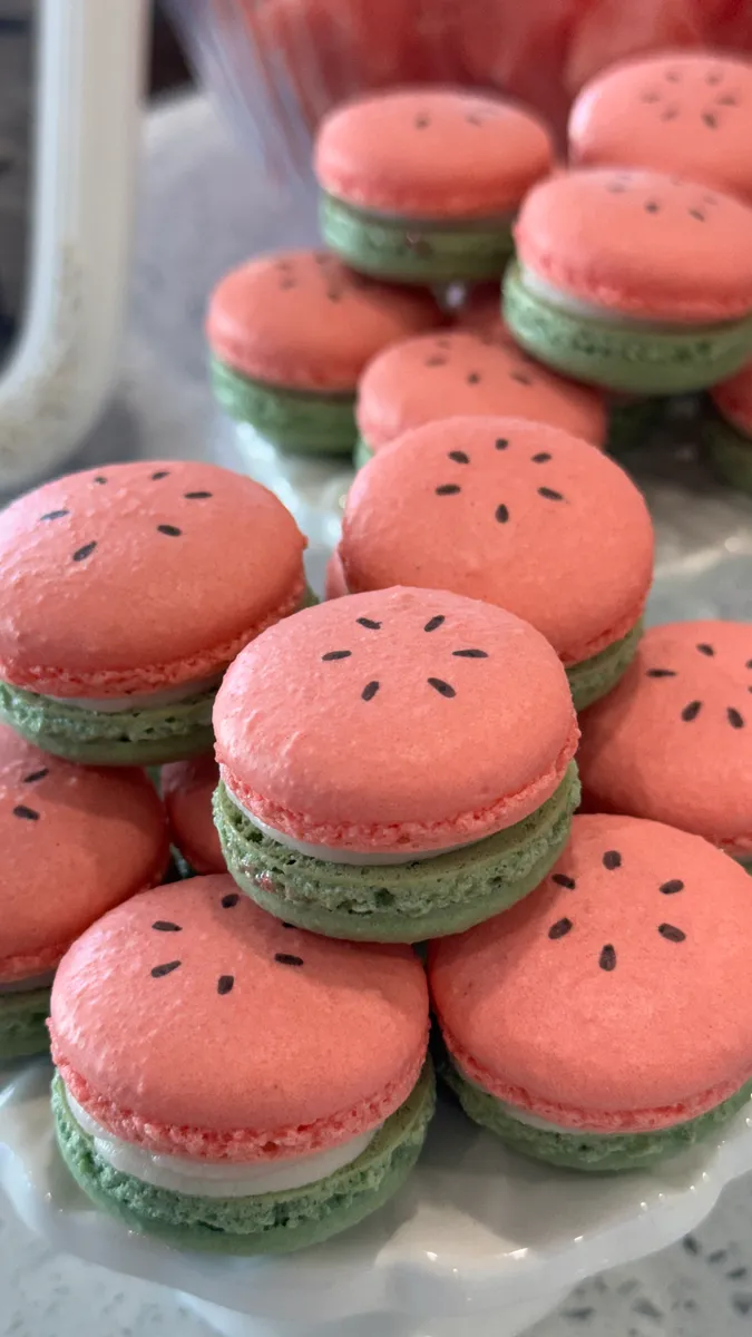 Watermelon macarons with pink tops, green shells, and seed details
